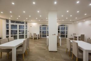 um restaurante com mesas e cadeiras brancas e janelas em Hotel Dapčević em Cetinje