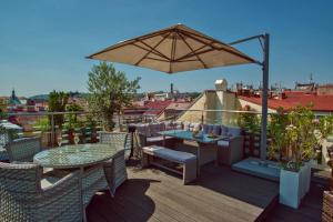 a patio with a table and an umbrella on a roof at Hotel Julian in Prague