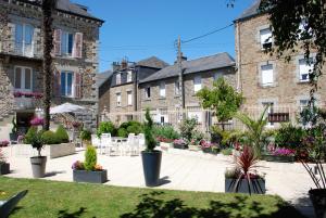 une cour avec des plantes en pot, des tables et des bâtiments dans l'établissement Hôtel Ariane & SPA, à Pontorson