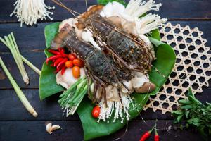 deux homards sur une plaque verte avec des légumes sur une table dans l'établissement Escalade Experience, à Cam Ranh