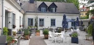 a patio with white chairs and tables and umbrellas at Hotell Slitebaden in Slite