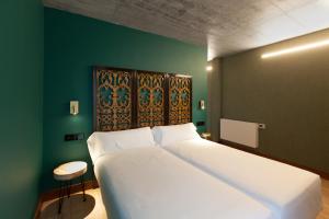 - une chambre avec un grand lit blanc et un mur vert dans l'établissement Eira Gundián, à Vedra