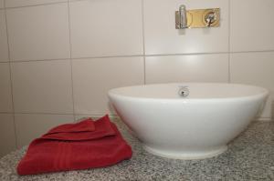 ビーベラハ・アン・デア・リスにあるGästehaus Adlerのバスルーム(白い洗面台、赤いタオル付)