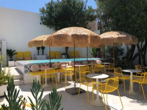 un patio con sillas amarillas, mesas y sombrillas en Hôtel Mademoiselle, en Juan-les-Pins