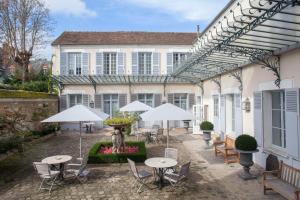 a patio with tables and umbrellas in front of a house at Hôtel de Londres in Fontainebleau