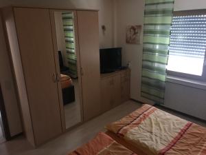 1 dormitorio con espejo, 1 cama y TV en Ferienwohnung Lippert, en Künzell