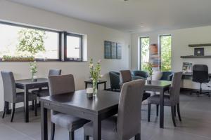 a dining room with tables and chairs and windows at B&B Molmento in Mol