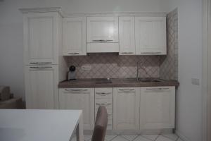 a white kitchen with white cabinets and a table at L'Orchidea Bianca in Cagliari