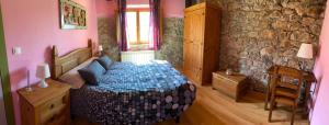 1 dormitorio con cama y pared de piedra en Alojamientos Casa San Apartamentos, en Besande