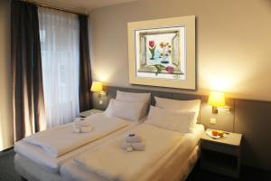 ein Hotelzimmer mit einem Bett mit zwei Teddybären darauf in der Unterkunft Altstadthotel Augsburg in Augsburg