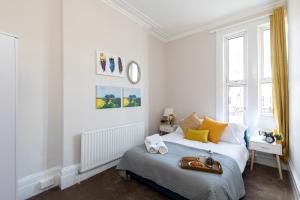 a bedroom with white walls and a bed with yellow pillows at homely - Central London King’s Cross Apartments in London