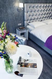 a room with a bed and a table with a magazine and flowers at Status Apartments in Kyiv