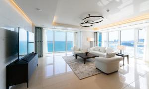 a living room with white furniture and large windows at Grand Lct Residence in Busan