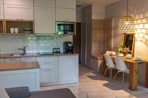 a kitchen with white cabinets and a table with chairs at Apartament "Zacisze" z tarasem in Ostróda