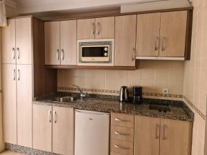 a kitchen with a sink and a microwave at Apartamentos El Barrio in Nerja