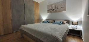 a bedroom with a bed with two blue pillows on it at Apartmani Tisno TM in Tisno