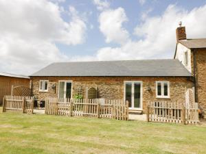 a brick house with a wooden fence in front of it at Oak Barn in Daventry