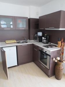 a kitchen with brown cabinets and a stove top oven at Etara 1 Apartment Complex in Sveti Vlas