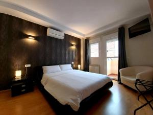 a bedroom with a large white bed and a chair at APARTAMENTOS SANTA JULIANA in Madrid