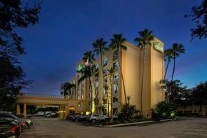 a hotel with palm trees in a parking lot at La Quinta by Wyndham West Palm Beach Airport in West Palm Beach