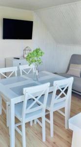 une table et des chaises blanches avec un vase et une plante dans l'établissement Apartament Gościnny Zakątek, à Sumowo