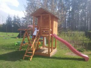 a girl climbing up a ladder on a play house at Apartament Gościnny Zakątek in Sumowo