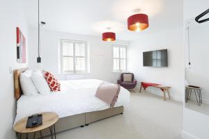a white bedroom with a bed and a chair at Hues - Castle Cary in Castle Cary