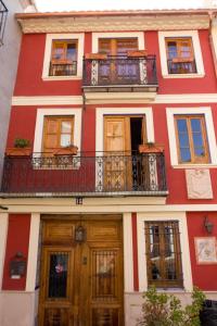 ein rot-weißes Gebäude mit einem Balkon und Türen in der Unterkunft A la Sombra de la Torre in Serra