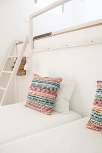 
a white bed with pillows and pillows on top of it at Peneco Albufeira GuestHouse in Albufeira
