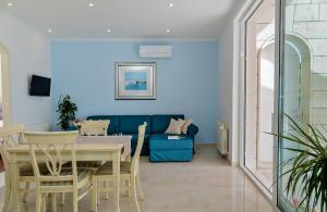 a living room with a table and a blue couch at Apartmani D&D Sosič in Brela