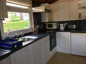 a kitchen with white cabinets and a sink and a window at Tranquilo cabanas in Carmarthen