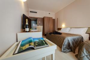 a hotel room with a bed and a table with a book at Hotel Mirasole International in Gaeta