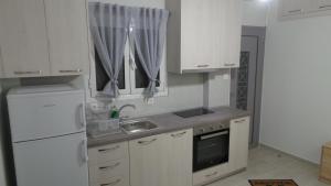 uma cozinha com armários brancos, um lavatório e um frigorífico em Katie's Blue House em Volos