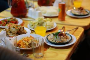 una mesa de madera cubierta con platos de comida y bebida en Madanur Hotel en Karakol
