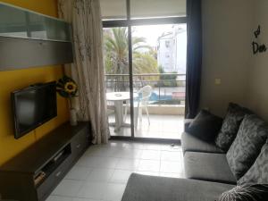 a living room with a couch and a tv and a balcony at Calella Flats & More in Calella