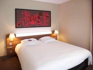 a bedroom with a large white bed with two pillows at Mercure Cholet Centre in Cholet