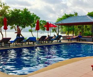 una piscina en un complejo con gente sentada en sillas en Cinnamon Beach Villas, en Lamai