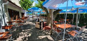 a row of tables and chairs with blue umbrellas at Hotel Post in Sargans