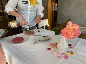 una mujer está preparando comida en una mesa con flores en Hotel Post, en Sargans