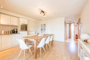 een keuken met een houten tafel en witte stoelen bij Modern and Large 2 bedroom apartment in Middelkerke in Middelkerke