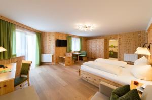 ein Hotelzimmer mit einem großen Bett und einem Schreibtisch in der Unterkunft Hotel Waidachhof in Kössen