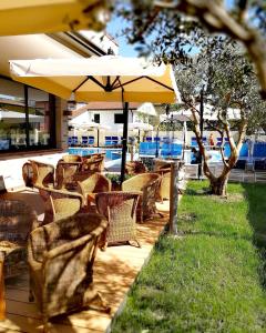eine Außenterrasse mit Stühlen und einem Sonnenschirm in der Unterkunft Hotel & Wellness Fra I Pini in Lignano Sabbiadoro