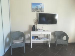 um quarto com duas cadeiras e uma mesa branca com uma televisão em Les Arums de Fondeminjean em Vertheuil-en-Médoc