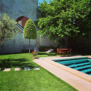 a backyard with a swimming pool and a table and a lawn at Le petit hotel in Saint-Rémy-de-Provence