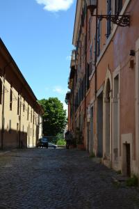 a person walking down a cobblestone street between buildings at Colosseum relax family apartament in Rome