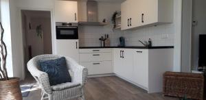 a kitchen with white cabinets and a chair at in de Boomgaard in Burgh Haamstede