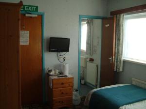 a bedroom with a bed and a tv on the wall at Tremains Guest House in Bridgend