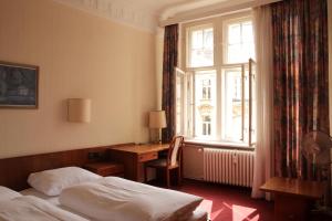 um quarto com uma cama, uma secretária e uma janela em Kurfürst am Kurfürstendamm em Berlim