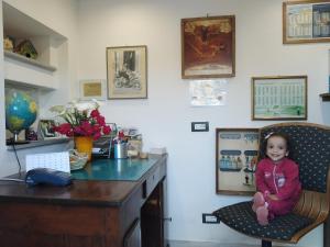 a little girl sitting on a chair in a kitchen at Agriturismo Fattoria Podere Peciano in Cortona