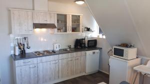 a kitchen with white cabinets and a white microwave at Appartement Esta in Buren